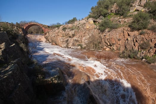 It is a Roman bridge that could belong to the primitive via Herculea, linking the ancient Oretania with the Spanish Levant, 3rd century a. d. C.. Is the landscape a beautiful formation of granitic rocks that are precipitating the River Guarrizas, forming two spectacular waterfalls that save the unevenness caused by the failure of Linares.