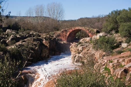 It is a Roman bridge that could belong to the primitive via Herculea, linking the ancient Oretania with the Spanish Levant, 3rd century a. d. C.. Is the landscape a beautiful formation of granitic rocks that are precipitating the River Guarrizas, forming two spectacular waterfalls that save the unevenness caused by the failure of Linares.