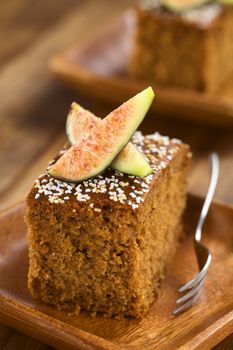 Fresh fig cake with fig wedges on top served on wooden plate with pastry fork (Selective Focus, Focus on the front of the fig wedge)