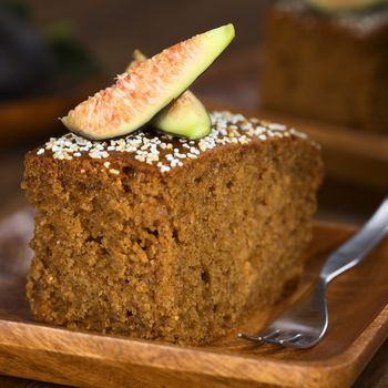 Fresh fig cake with fig wedges on top served on wooden plate with pastry fork (Selective Focus, Focus on the front of the fig wedge)