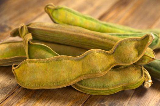 Peruvian fruit called Pacay (lat. Inga feuilleei), which is a podded fruit of which the sweet white pulp surrounding the seeds is being eaten (Selective Focus, Focus on the lower two thirds of the first pacay))