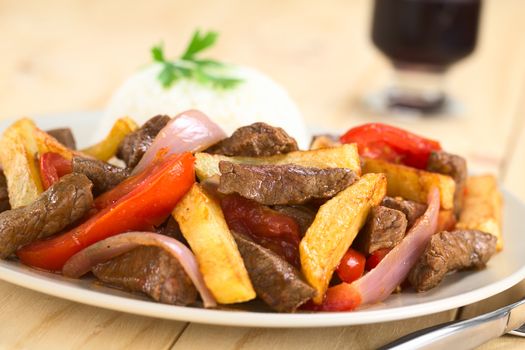 Peruvian dish called Lomo Saltado made of beef, tomato, red onion and French fries, served with rice (Selective Focus, Focus on the horizontal beef piece in the middle of the image)