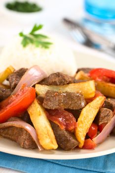 Peruvian dish called Lomo Saltado made of beef, tomato, red onion and French fries, served with rice (Selective Focus, Focus one third into the dish)