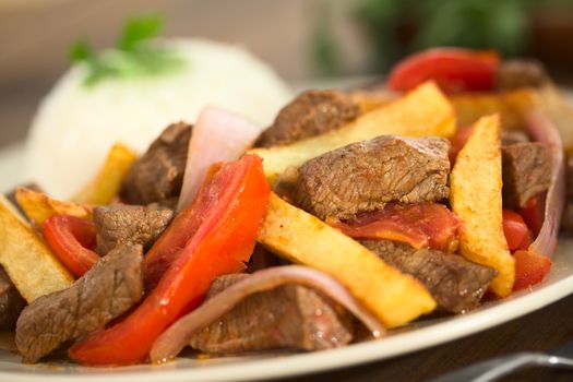 Peruvian dish called Lomo Saltado made of beef, tomato, red onion and French fries, served with rice (Selective Focus, Focus one third into the dish)