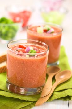 Traditional Spanish cold vegetable soup made of tomato, cucumber, bell pepper, onion, garlic and olive oil served in glasses (Selective Focus, Focus on the front of the vegetables on the top of the soup)