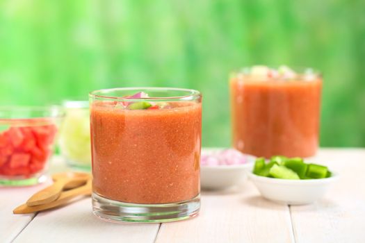 Traditional Spanish cold vegetable soup made of tomato, cucumber, bell pepper, onion, garlic and olive oil served in glasses (Selective Focus, Focus on the front of the glass rim)