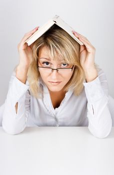 The girl in glasses looking out from under the book