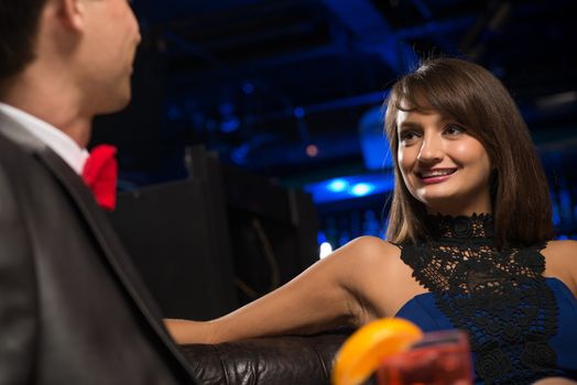 portrait of a woman in a nightclub, sitting on the couch and talking with man