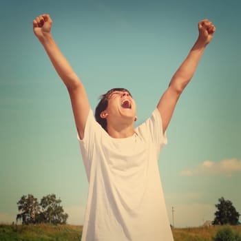 Toned photo of happy teenager with hands up outdoor