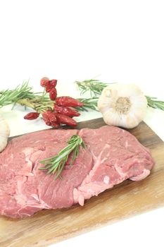 Ribeye steak with garlic, chilli and rosemary on a light background