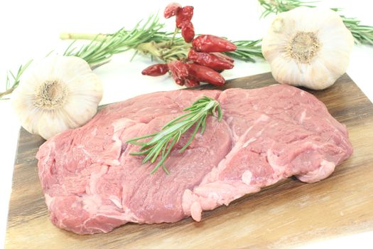 Ribeye steak with garlic and rosemary on a light background