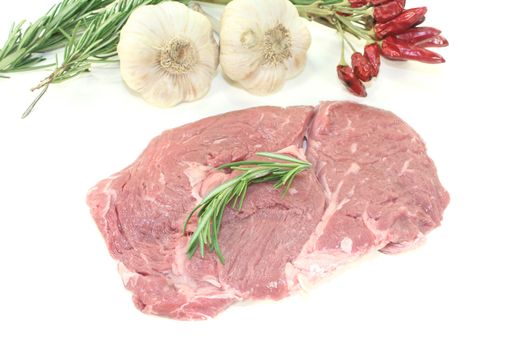 fresh raw Ribeye steak with rosemary on a light background