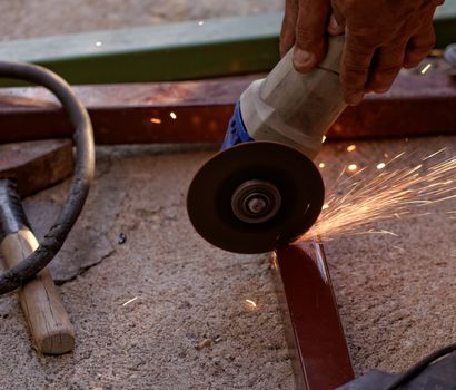 Metal sawing with hand grinder. Sparks while grinding iron.