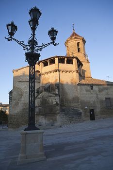 Sunrise in square on May 1, with side front and source of the church of San pablo and lamppost, Ubeda, Jaen province, Spain