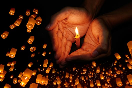 Candle light in hand with Floating lantern in the night sky background, Pray concept
