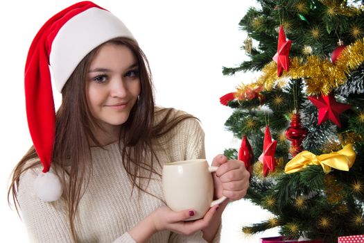 Pretty teenage girl with coffee mug under Christmas tree over white