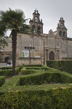 Cloudy day in Church of Santa Maria of the Reales Alcazares from Vazquez de Molina square with hedges in the foreground, Ubeda, Spain