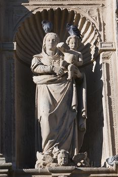 Holy Mary with child with two placed pigeons, sculpture inside a niche, relief of the Front of the chapel of El Salvador of Ubeda, Jaen province, Spain