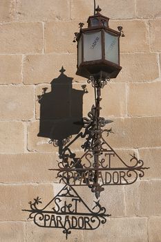 Lamppost on the stone wall of the Hostelry from Ubeda, Jaen province, Spain