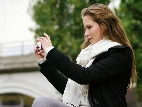 Photo of a beautiful woman using her smartphone to take photos. Photo is from the PhotoWalk in Berlin during Microstock Expo.