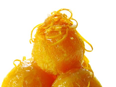 Stack of naval oranges topped  with rind and orange syrup.