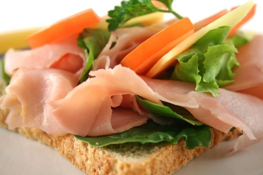 Ham, lettuce, tomato and cheese open sandwich on wholemeal bread.