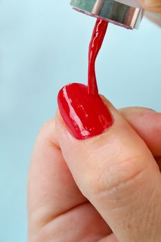 Female carefully painting her fingernails.