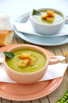 Delicious bowls of pea soup with fresh mint and crusty bread.