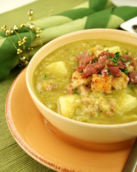 Chunky pea and ham soup with croutons and ham with a parsley garnish.