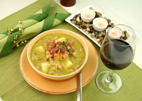 Chunky pea and ham soup with croutons and ham with a parsley garnish.
