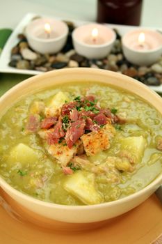 Chunky pea and ham soup with croutons and ham with a parsley garnish.