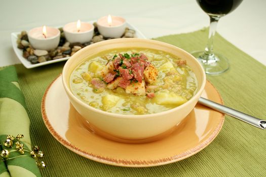 Chunky pea and ham soup with croutons and ham with a parsley garnish.