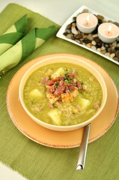 Chunky pea and ham soup with croutons and ham with a parsley garnish.