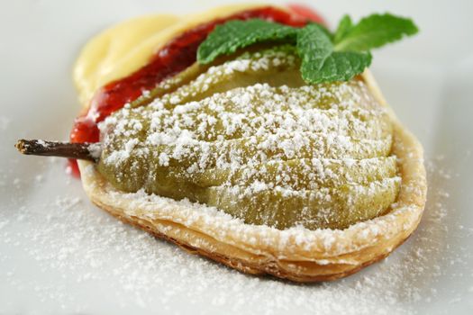 Delicate baked pear tartlet with custard and strawberry jam.