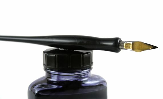 Vintage pen lying on top of a bottle of ink.