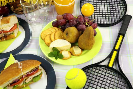 Fresh fruit and cheese laid out amongst a picnic spread.