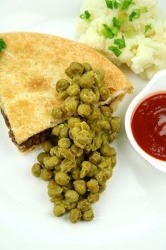 Meat pie with mushy peas and mashed potato and ketchup.