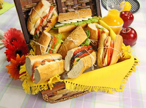 Selection of food and rolls for a picnic with a hamper, basket and fruit.