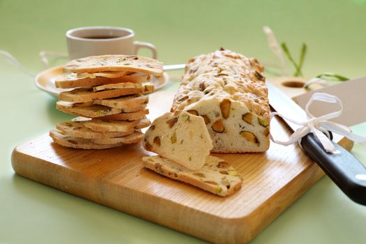 Fresh baked sweet pistachio bread sliced on a bread board with coffee.