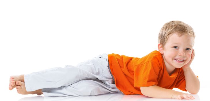 Adorable happy boy lying on the floor in studio. Isolated of white background.