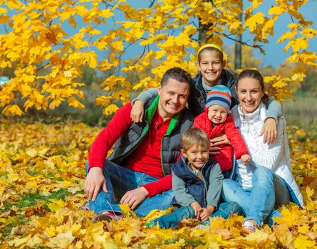 Happy family with three kids at beautiful autumn park