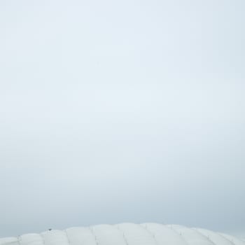 Inflated white roof stadium against cloudy sky