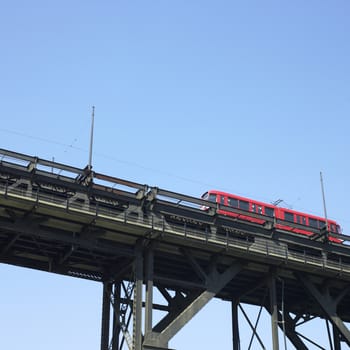 Red trolley car on tracks against blue sky