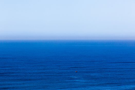 Clear blue ocean swells into blue distant horizon sky