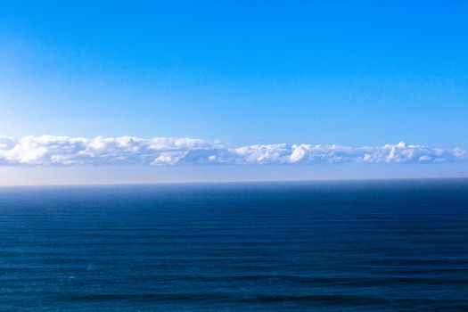 Clear blue ocean swells into blue distant horizon sky
