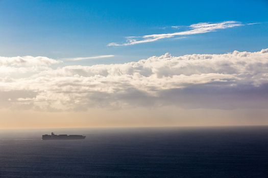 Ship with container cargo on the vast blue morning ocean on destination course.