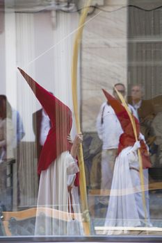 Two penitents reflected in a glass in a procession of holy week on Palm Sunday, Spain