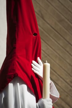 Detail penitent white holding a candle during Holy Week, Spain