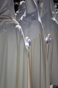 Detail penitent white holding a candle during Holy Week, Spain