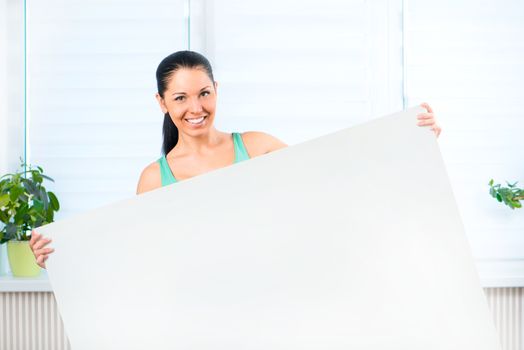 Portrait of happy young casual woman holding a blank signboard